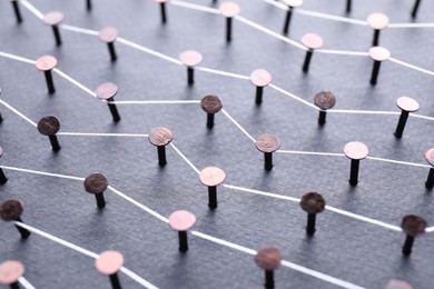 Photo of Network connection. Nails linked together by thread on black background, closeup