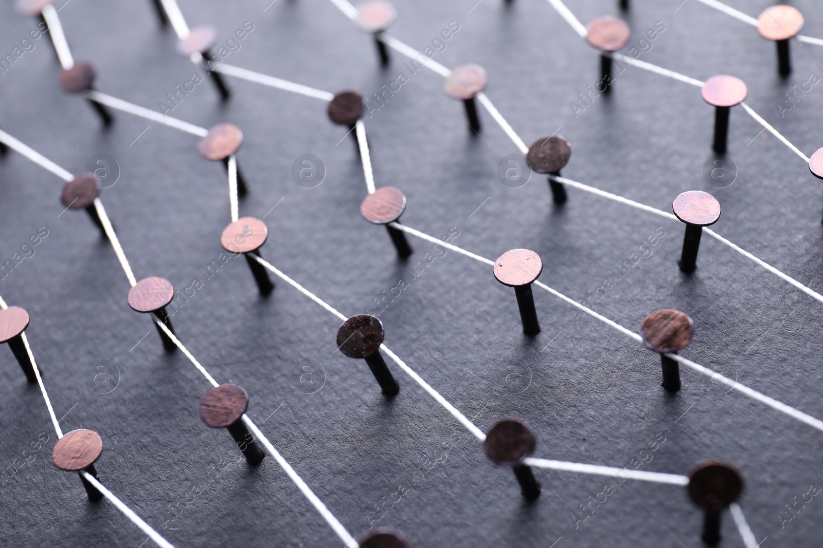 Photo of Network connection. Nails linked together by thread on black background, closeup