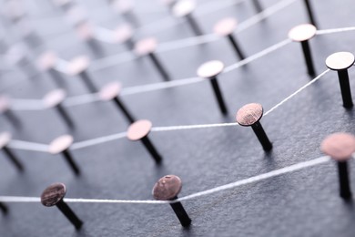 Photo of Network connection. Nails linked together by thread on black background, closeup