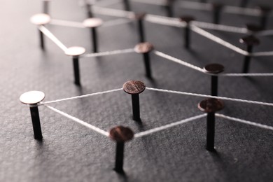 Photo of Network connection. Nails linked together by thread on color background, closeup