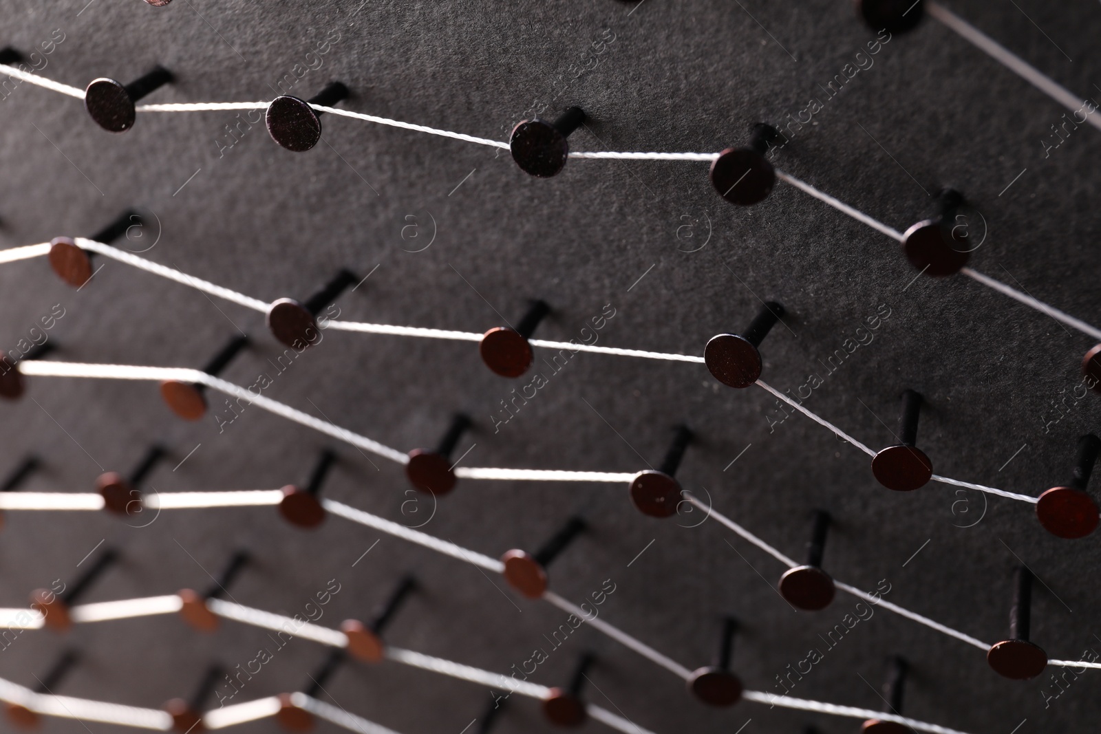 Photo of Network connection. Nails linked together by thread on black background, above view