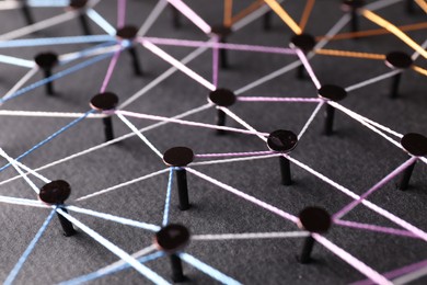 Photo of Network connection. Nails linked together by threads on black background, closeup