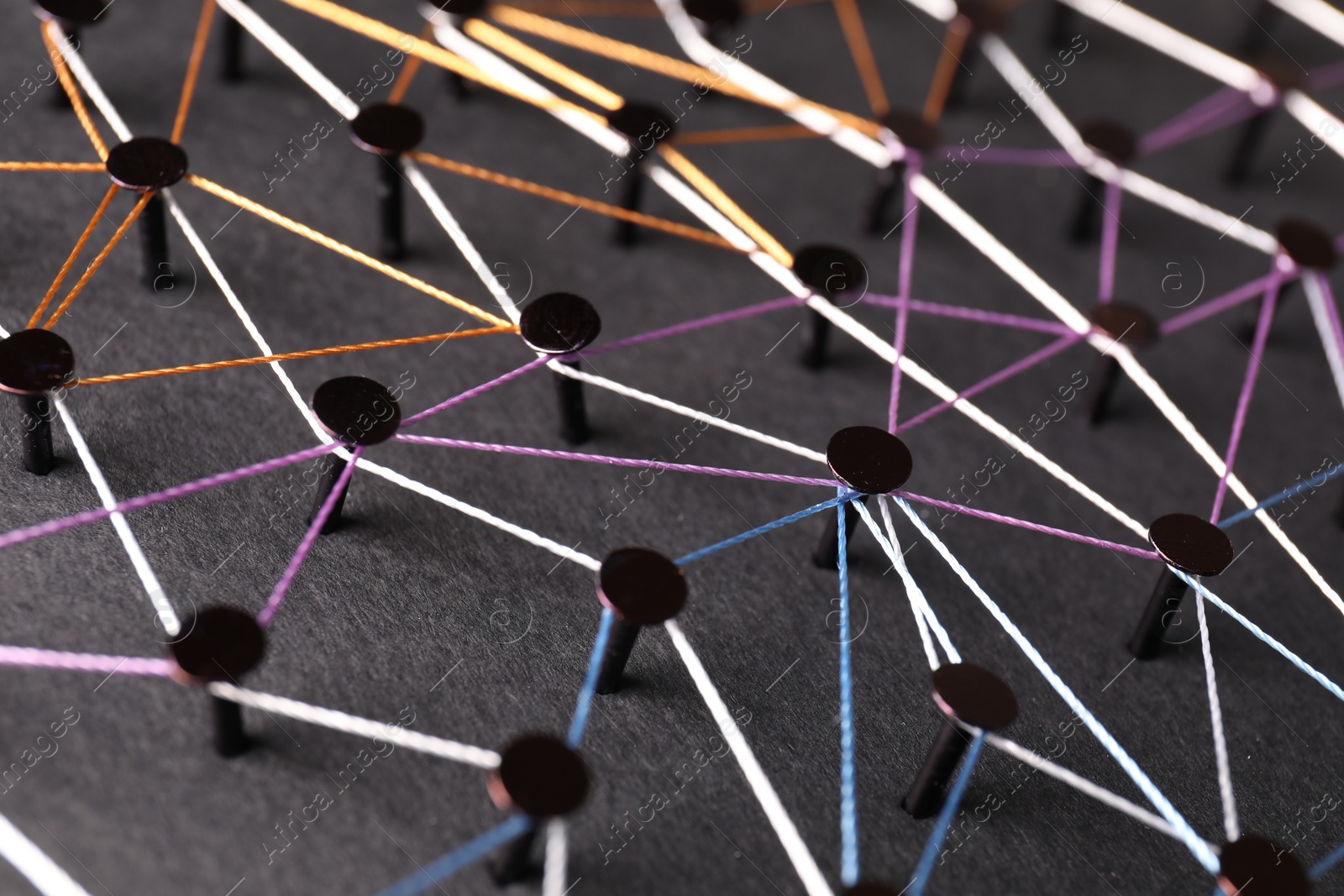 Photo of Network connection. Nails linked together by threads on black background, closeup