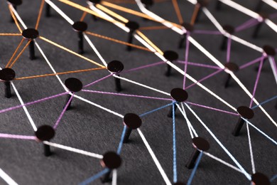 Photo of Network connection. Nails linked together by threads on black background, closeup