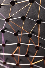 Photo of Network connection. Nails linked together by threads on black background, above view