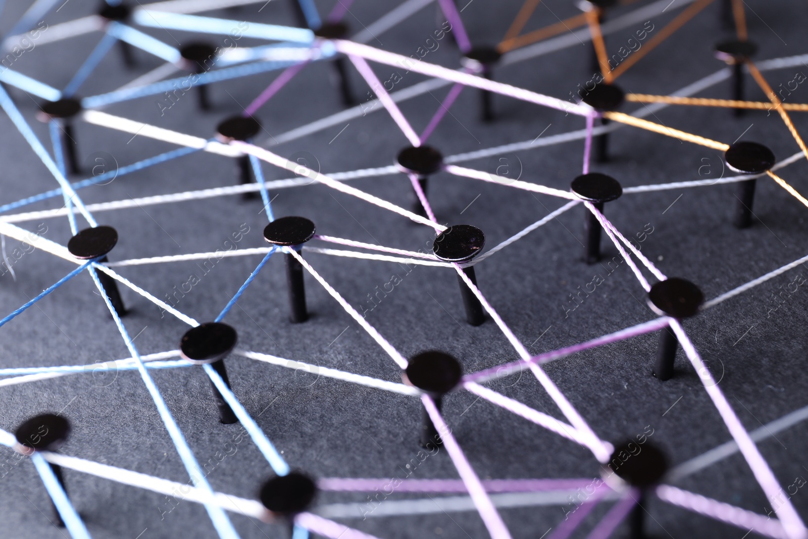 Photo of Network connection. Nails linked together by threads on black background, closeup