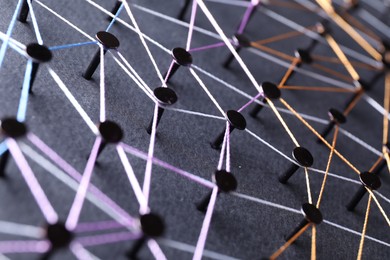 Photo of Network connection. Nails linked together by threads on black background, closeup