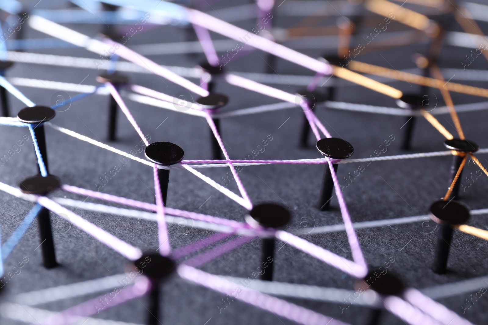 Photo of Network connection. Nails linked together by threads on black background, closeup