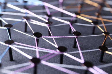 Photo of Network connection. Nails linked together by threads on black background, closeup