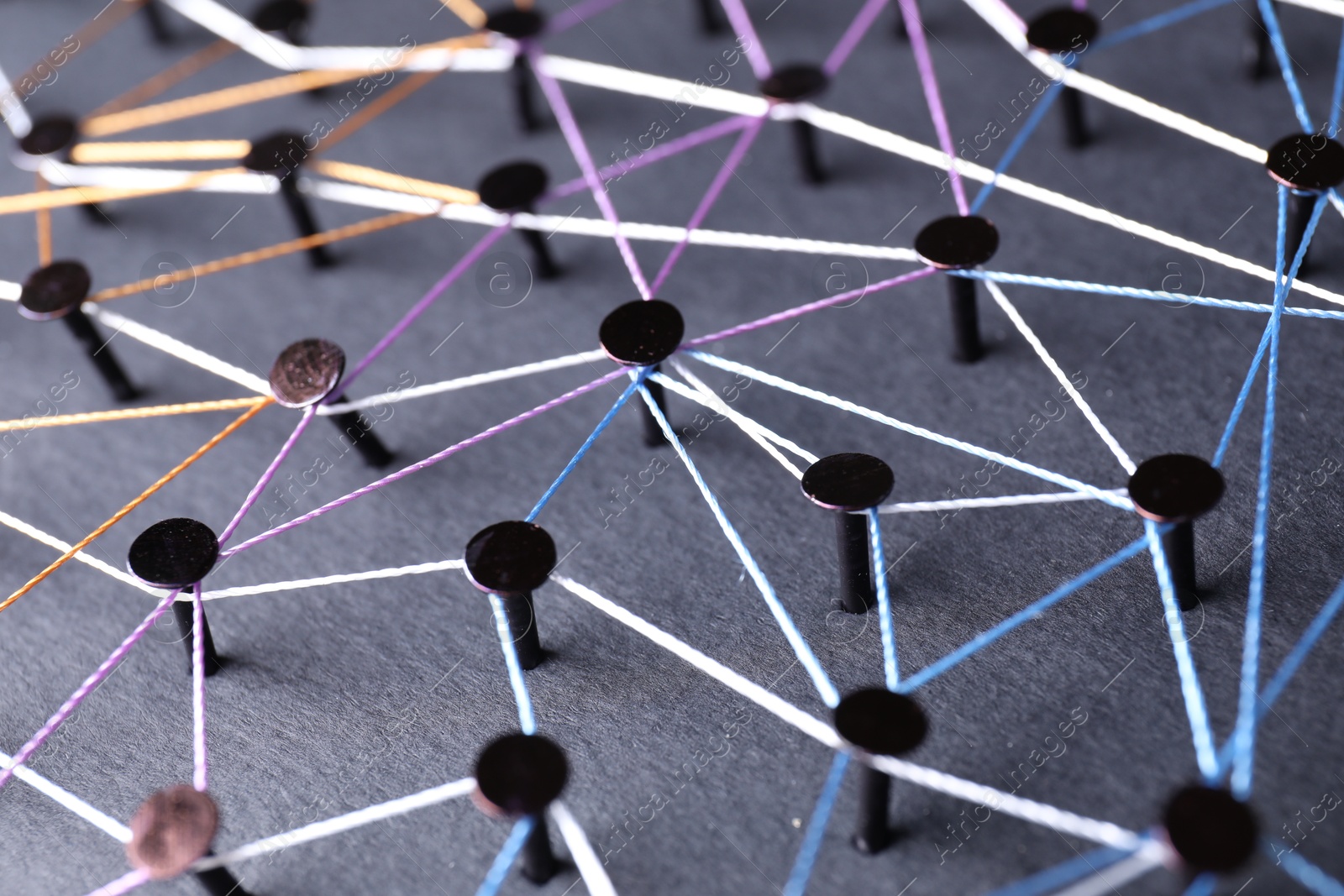 Photo of Network connection. Nails linked together by threads on black background, closeup