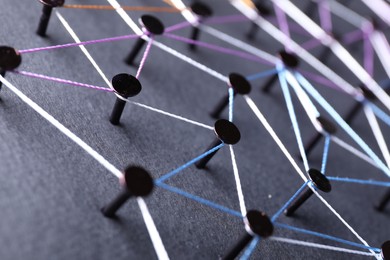 Photo of Network connection. Nails linked together by threads on black background, closeup