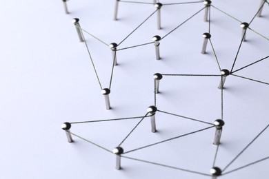 Photo of Network connection. Nails linked together by threads on white background, closeup