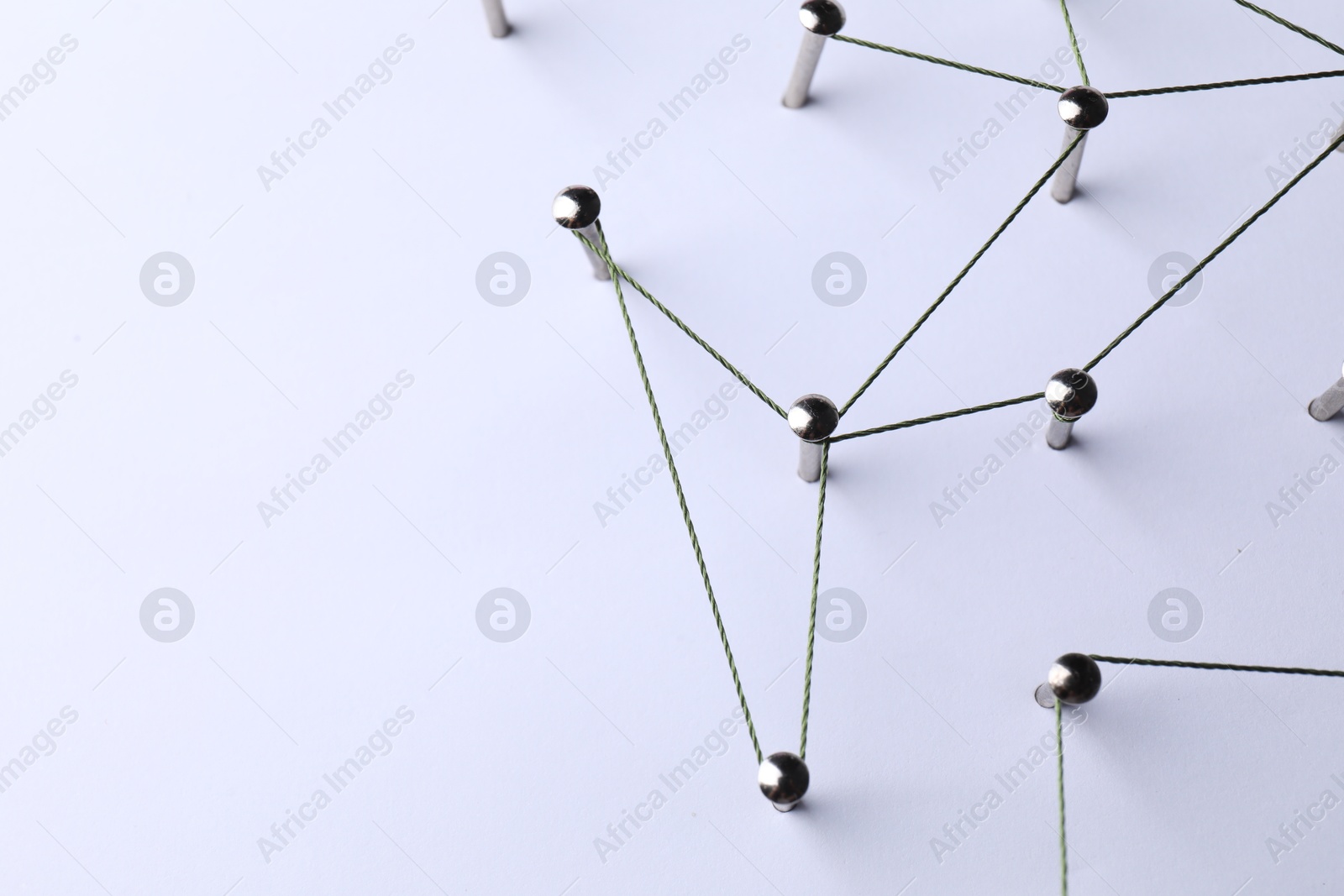 Photo of Network connection. Nails linked together by threads on white background, above view. Space for text