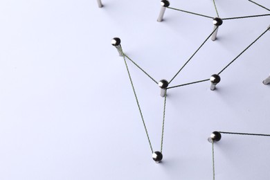 Photo of Network connection. Nails linked together by threads on white background, above view. Space for text