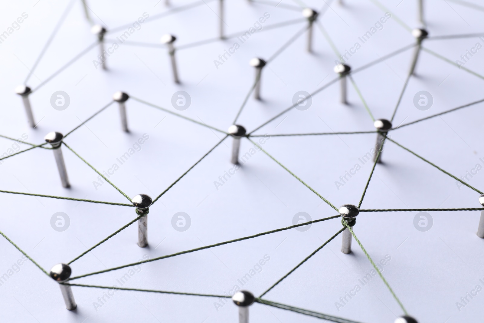 Photo of Network connection. Nails linked together by threads on white background, closeup