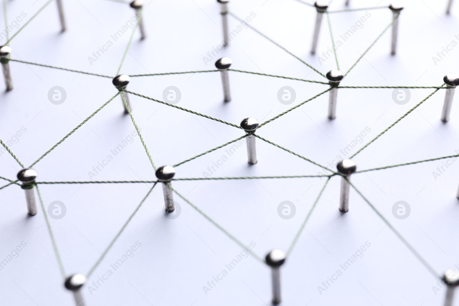 Photo of Network connection. Nails linked together by threads on white background, closeup