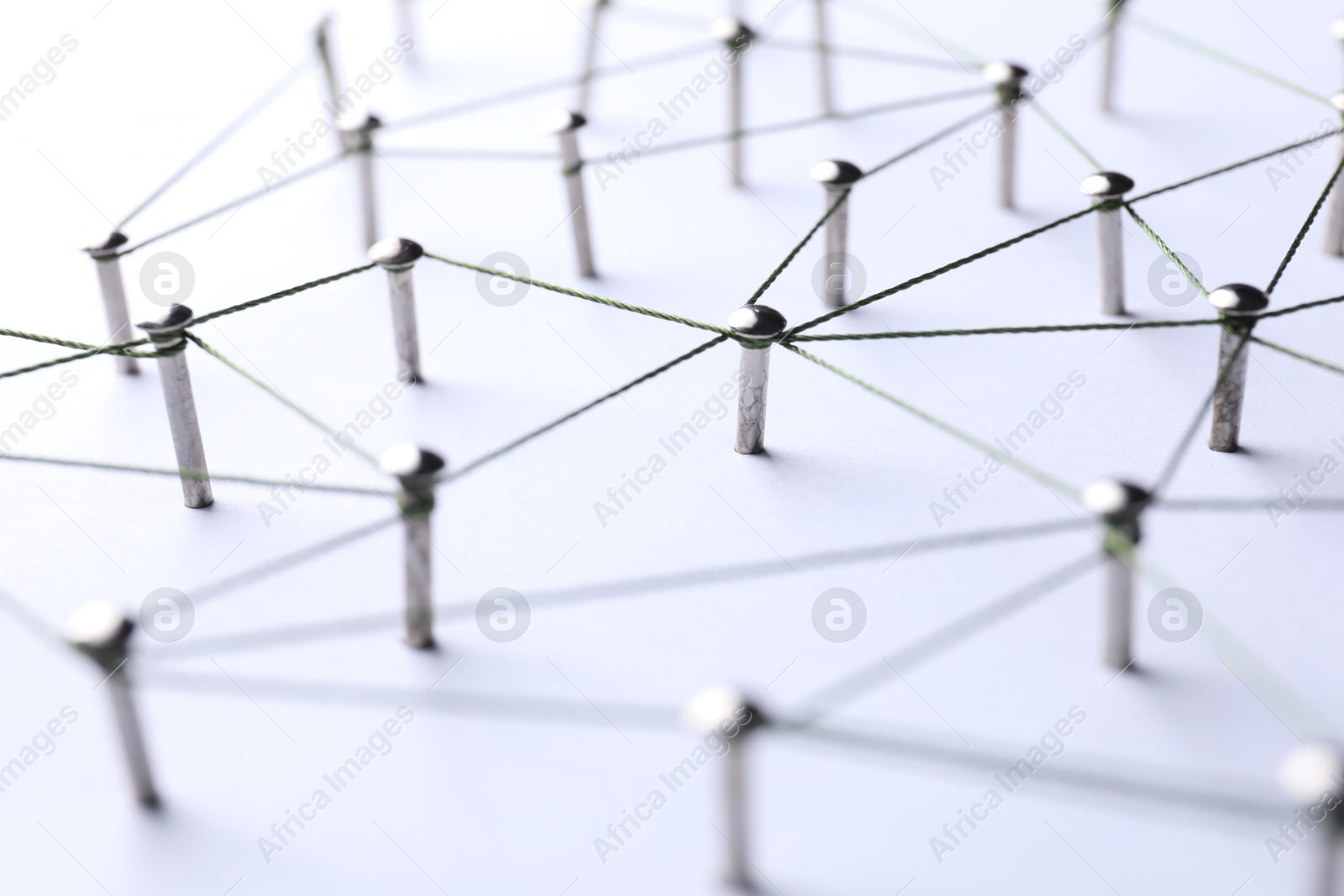 Photo of Network connection. Nails linked together by threads on white background, closeup