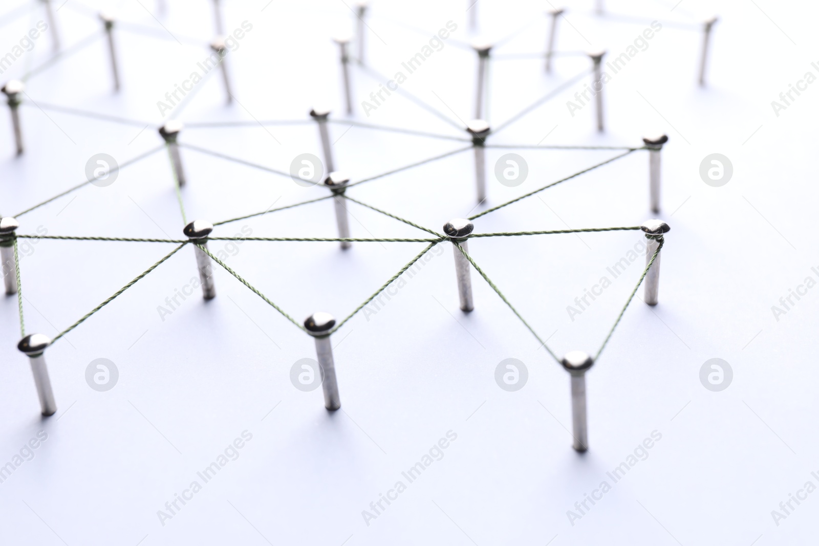 Photo of Network connection. Nails linked together by threads on white background, closeup