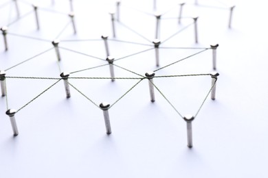 Photo of Network connection. Nails linked together by threads on white background, closeup