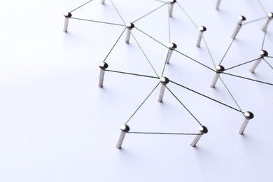 Photo of Network connection. Nails linked together by threads on white background, closeup