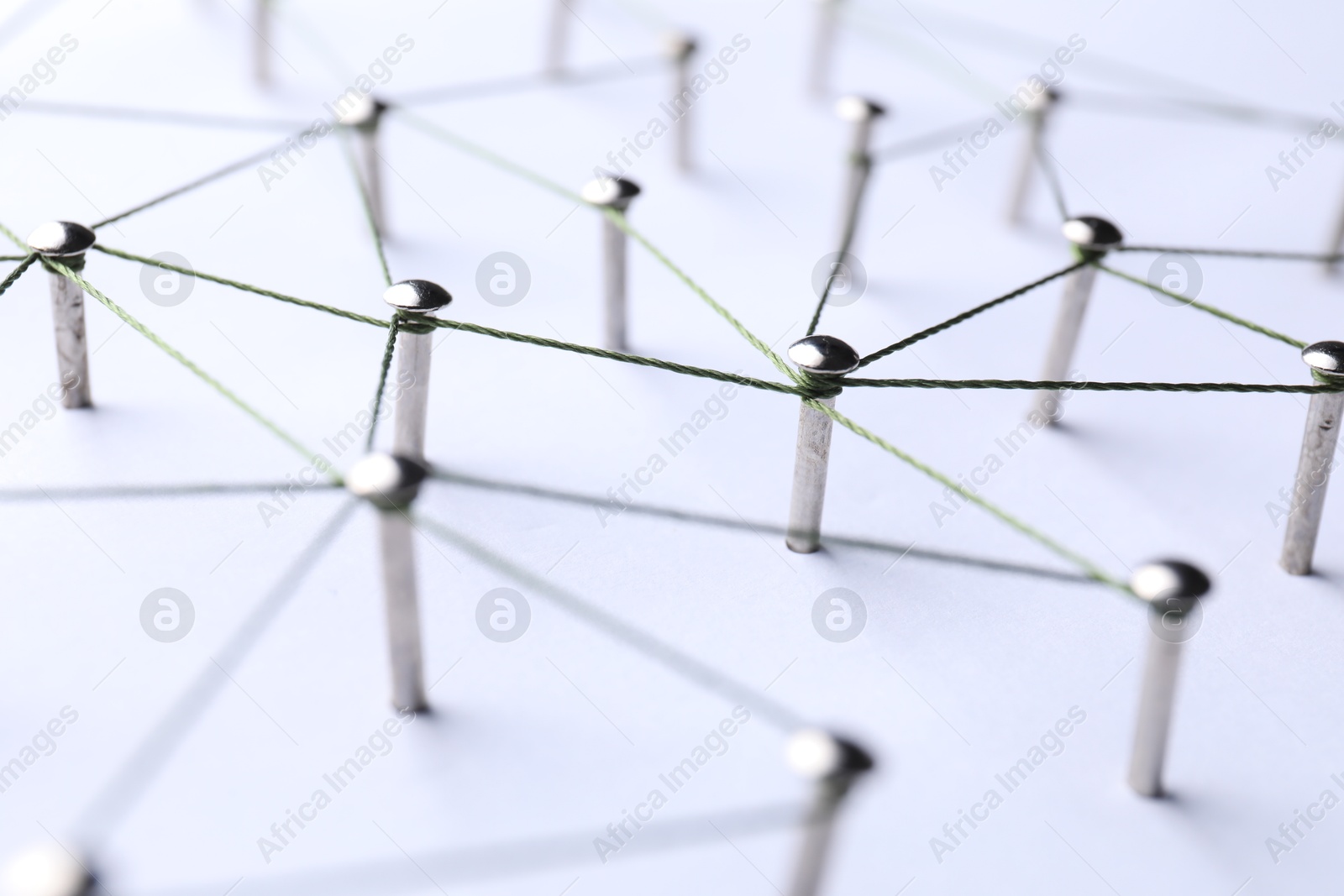 Photo of Network connection. Nails linked together by threads on white background, closeup