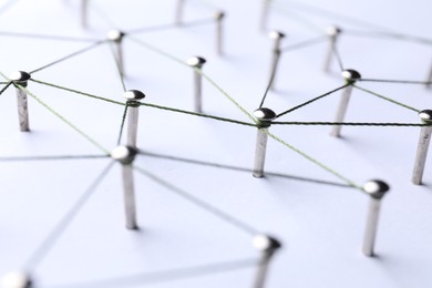 Photo of Network connection. Nails linked together by threads on white background, closeup