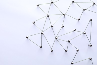 Photo of Network connection. Nails linked together by threads on white background, flat lay. Space for text