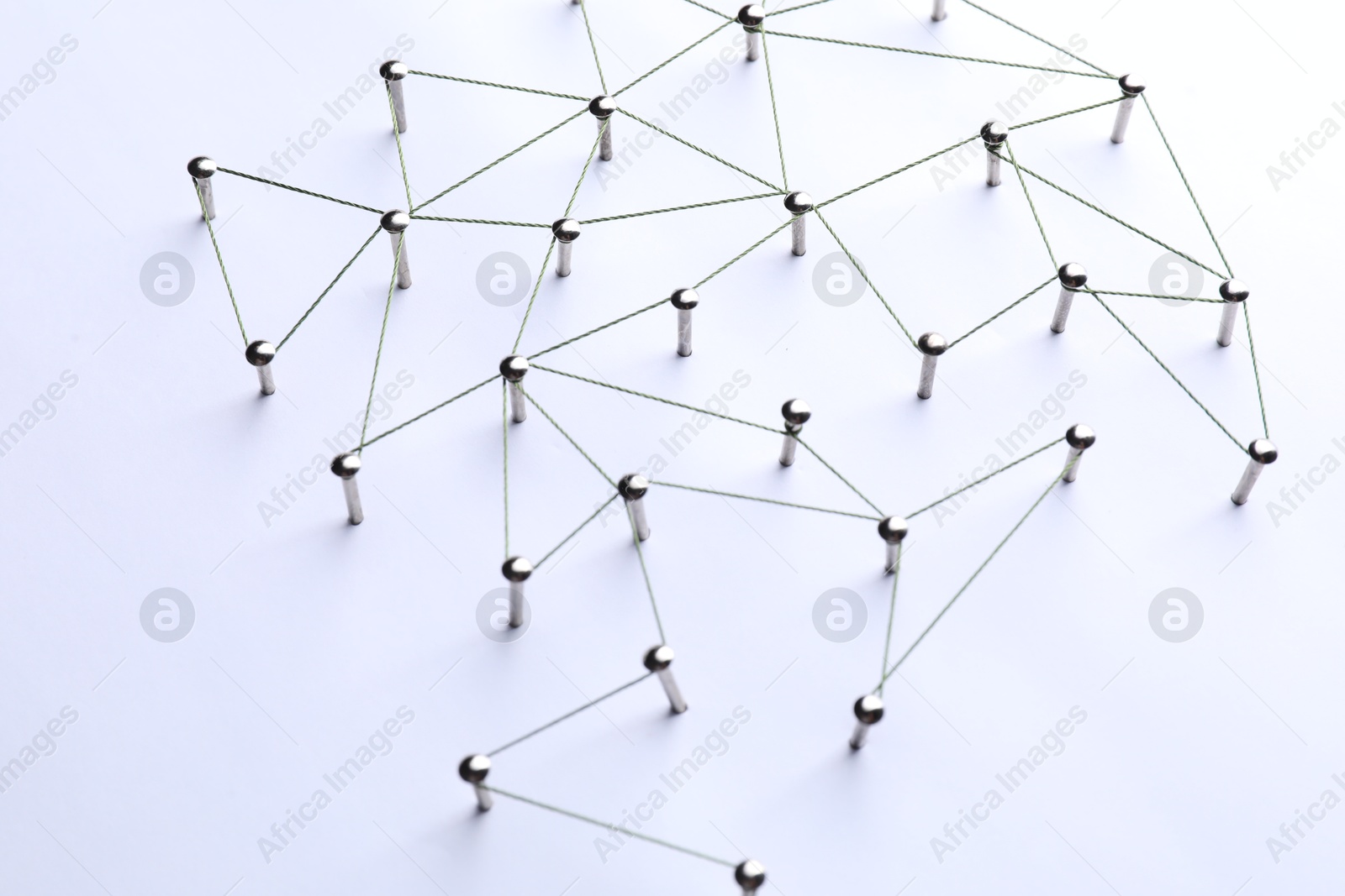 Photo of Network connection. Nails linked together by threads on white background, above view