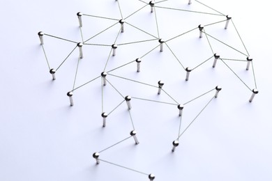 Photo of Network connection. Nails linked together by threads on white background, above view