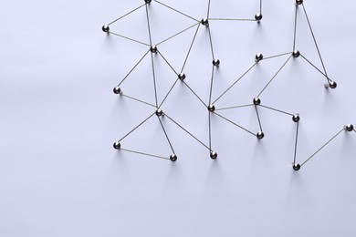 Photo of Network connection. Nails linked together by threads on white background, flat lay. Space for text