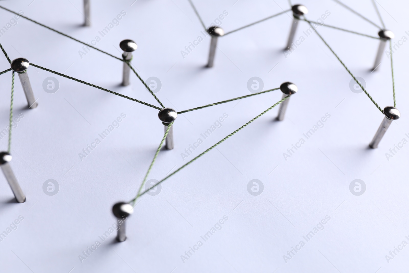 Photo of Network connection. Nails linked together by threads on white background, closeup