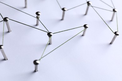 Photo of Network connection. Nails linked together by threads on white background, closeup