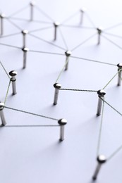 Photo of Network connection. Nails linked together by threads on white background, closeup