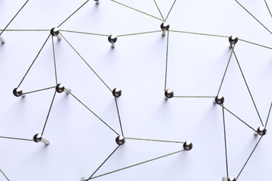 Photo of Network connection. Nails linked together by threads on white background, flat lay