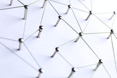 Photo of Network connection. Nails linked together by threads on white background, closeup