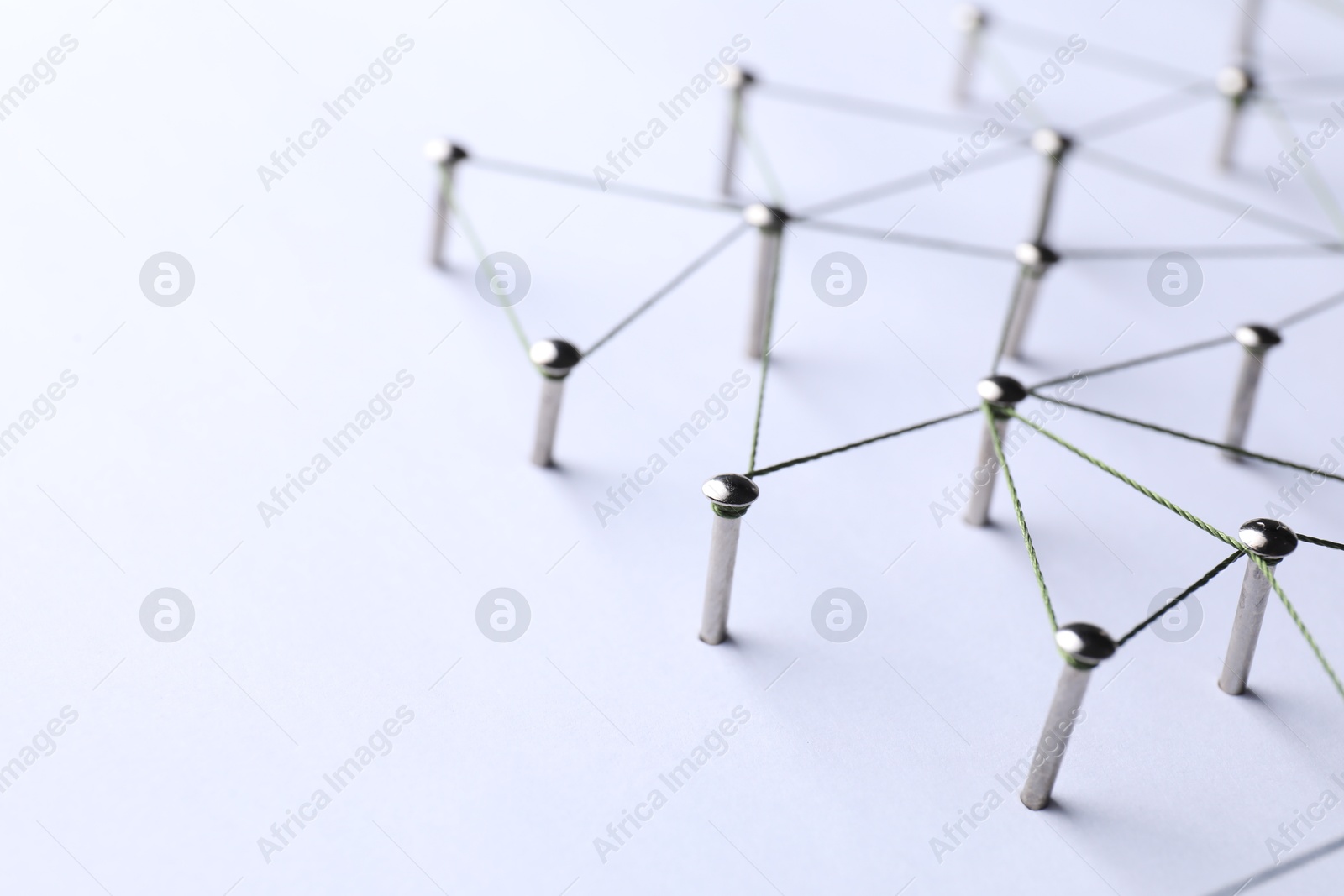 Photo of Network connection. Nails linked together by threads on white background, closeup. Space for text