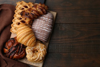 Photo of Different sweet pastries on wooden table, top view. Space for text