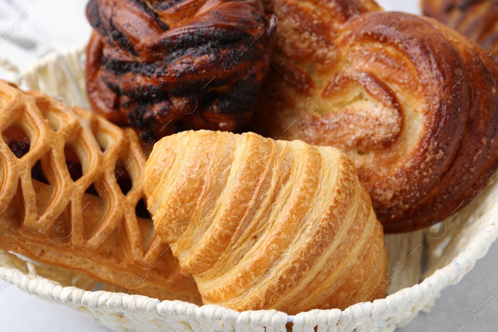 Photo of Different pastries in basket on light table, closeup