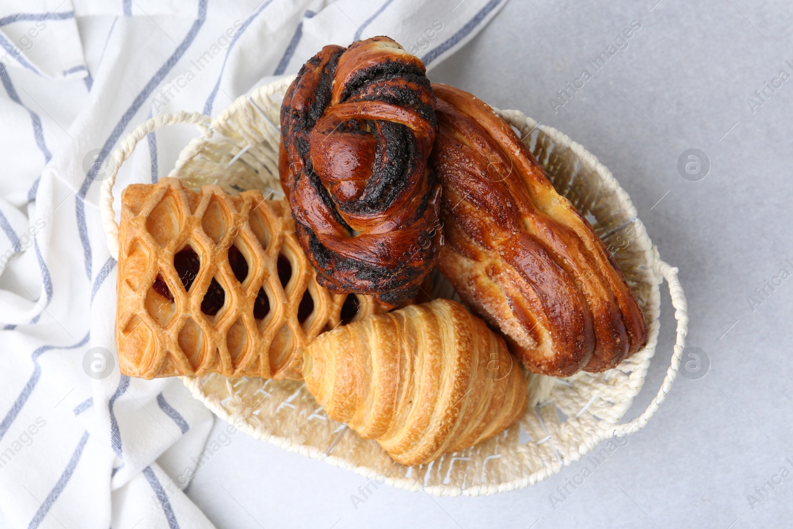 Photo of Different pastries in basket on light table, top view