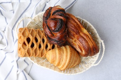 Photo of Different pastries in basket on light table, top view