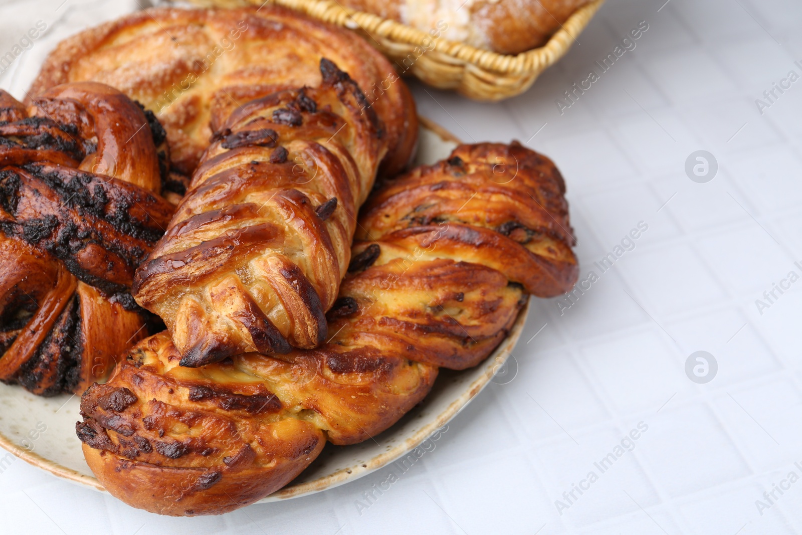 Photo of Different sweet pastries on white tiled table, closeup