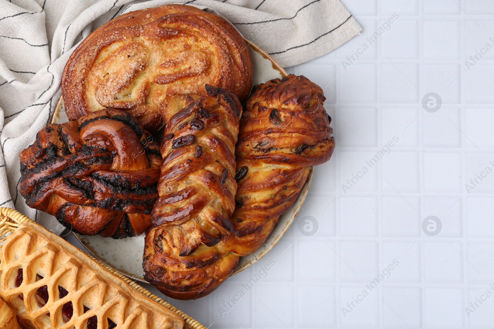 Photo of Different sweet pastries on white tiled table, top view. Space for text