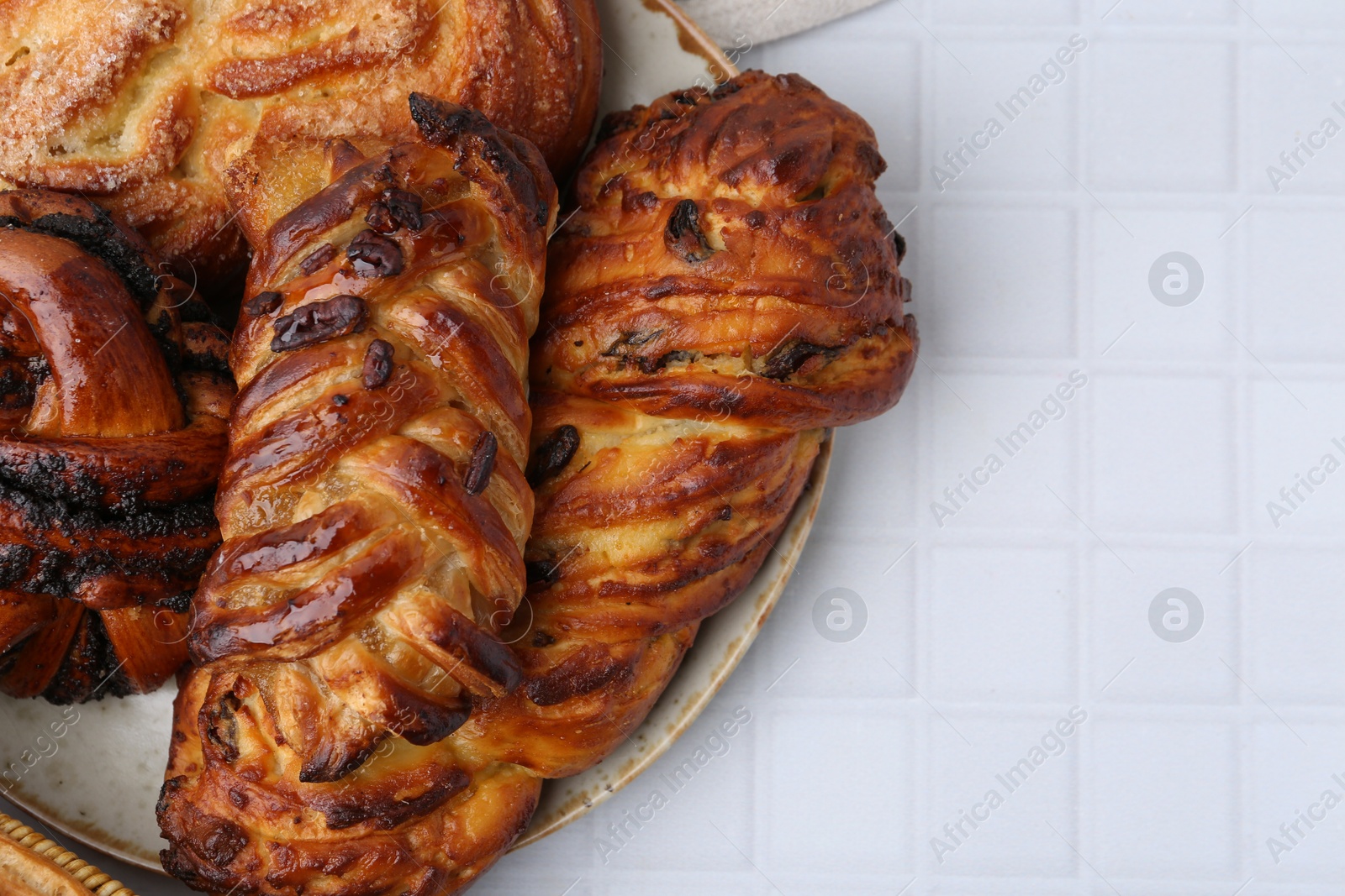 Photo of Different sweet pastries on white tiled table, top view. Space for text