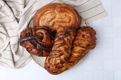 Different sweet pastries on white tiled table, top view