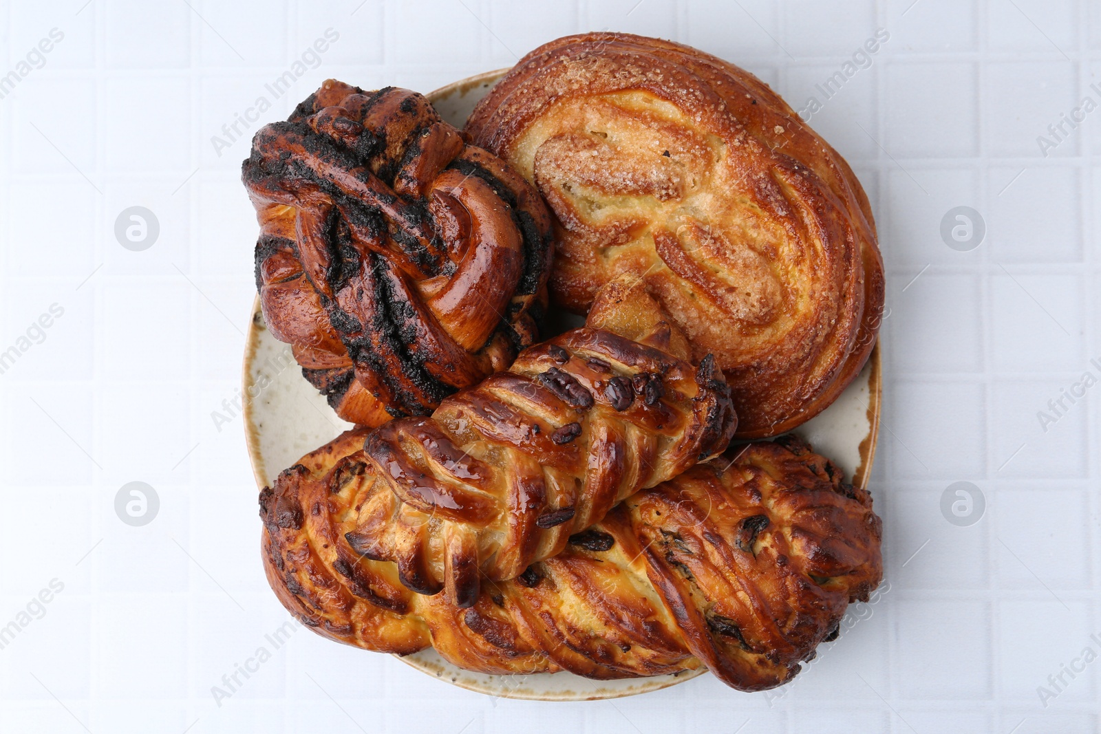 Photo of Different sweet pastries on white tiled table, top view