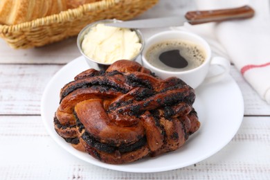 Photo of Delicious poppy seed pastry, butter and coffee on white wooden table, closeup