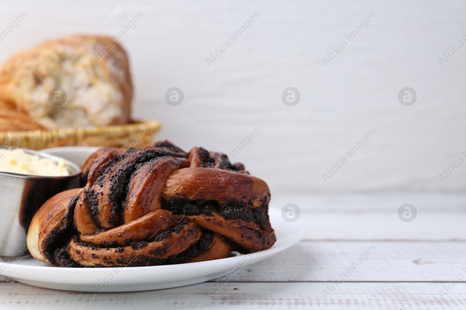 Photo of Delicious poppy seed pastry with butter on white wooden table. Space for text