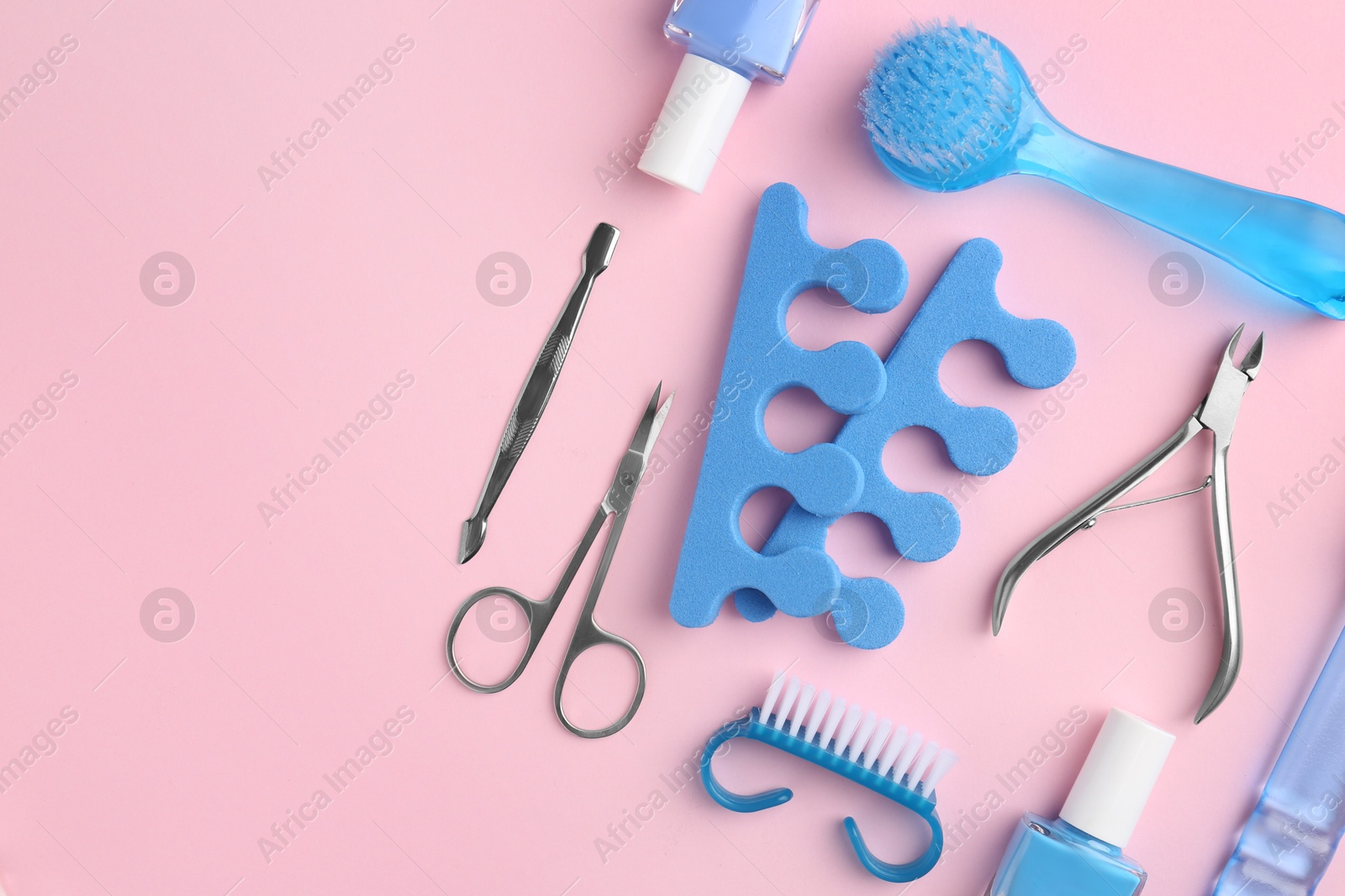 Photo of Set of pedicure tools on pink background, flat lay. Space for text