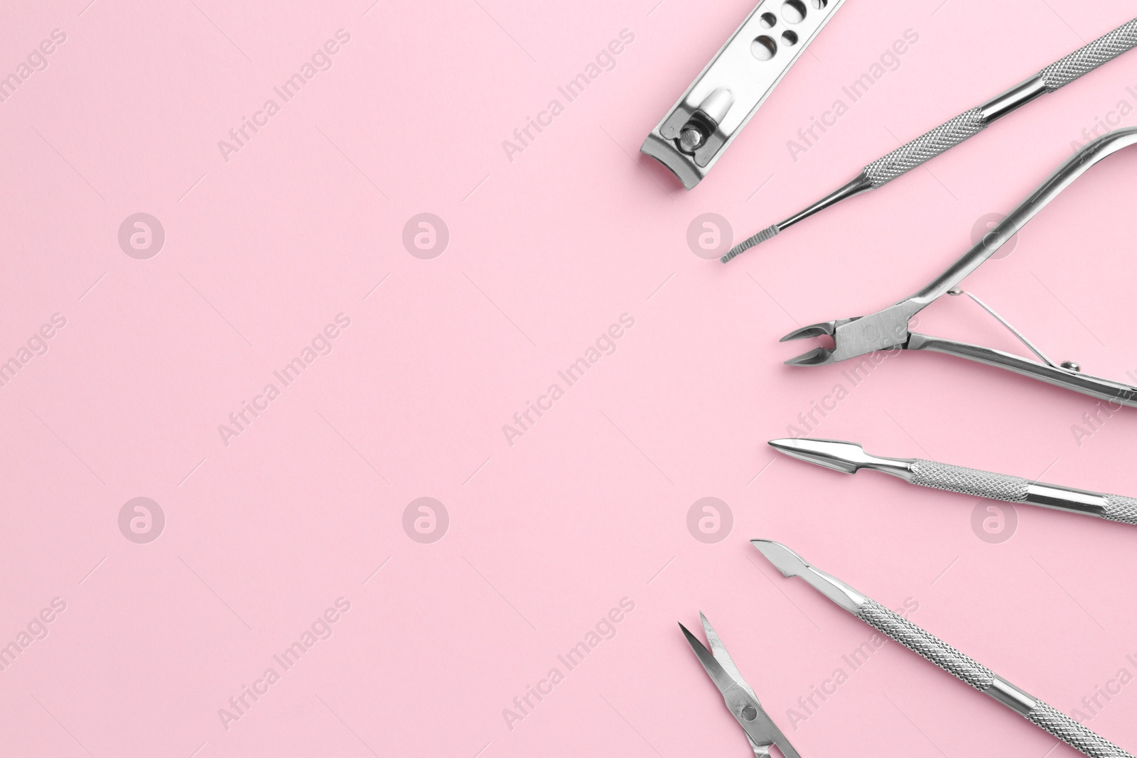 Photo of Set of pedicure tools on pink background, flat lay. Space for text