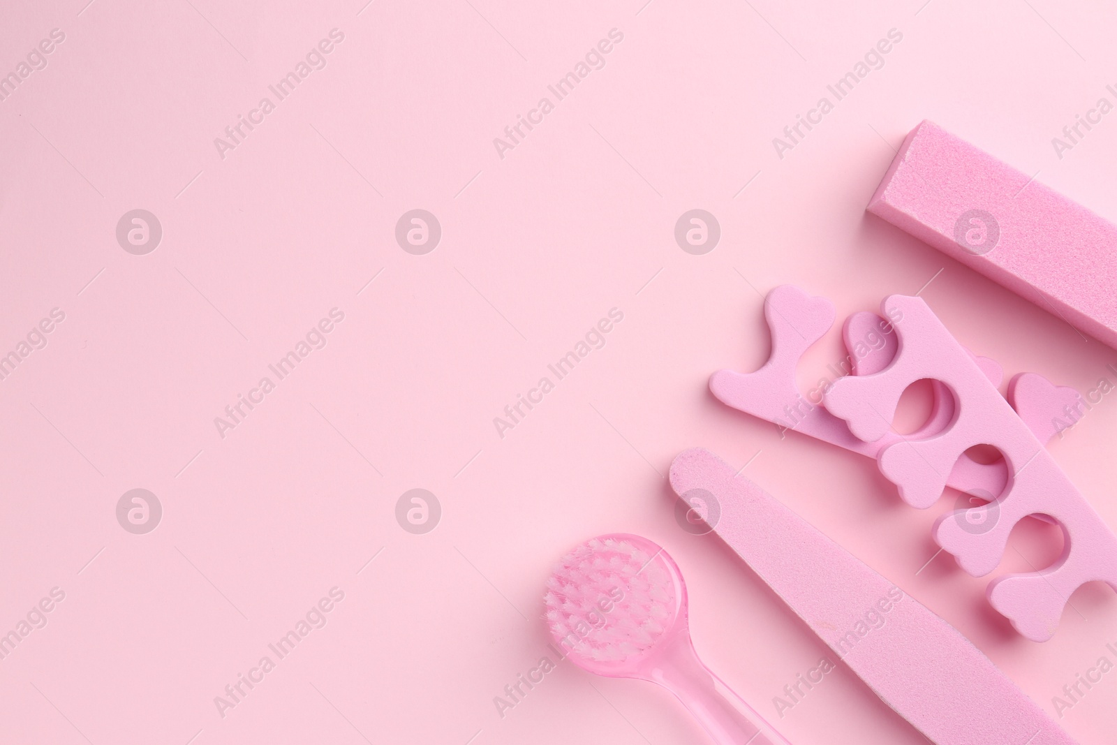 Photo of Set of pedicure tools on pink background, flat lay. Space for text